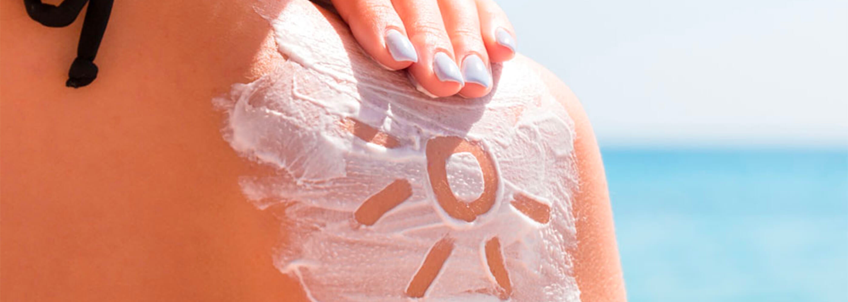 una spalla di ragazza al mare piena di crema con un sole disegnato