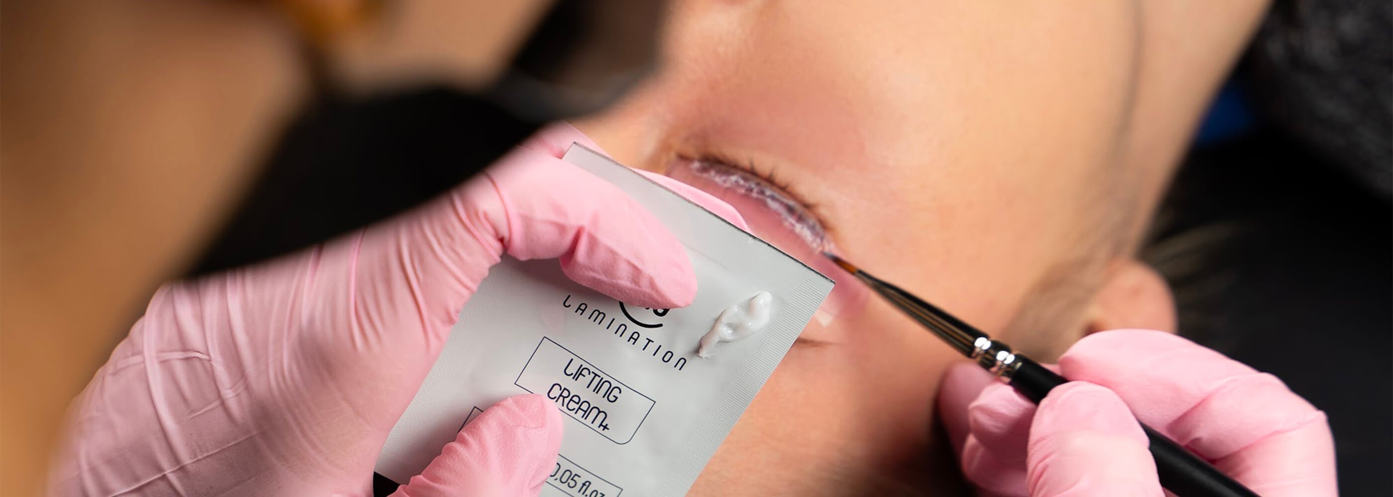 estetista esegue laminazione ciglia su una cliente reggendo la lifting cream di my lamination